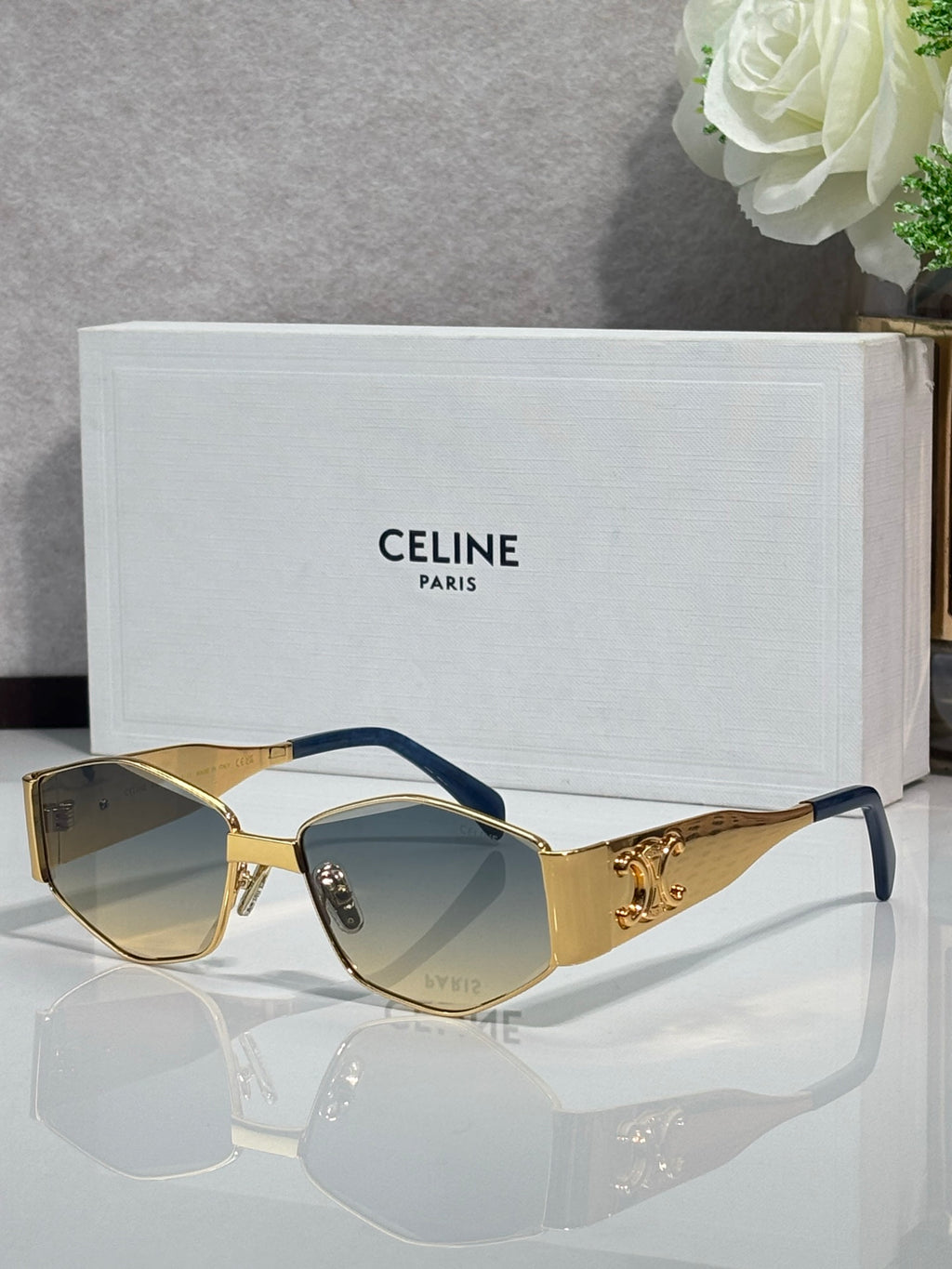 Gold sunglasses with light lenses and blue temple accents