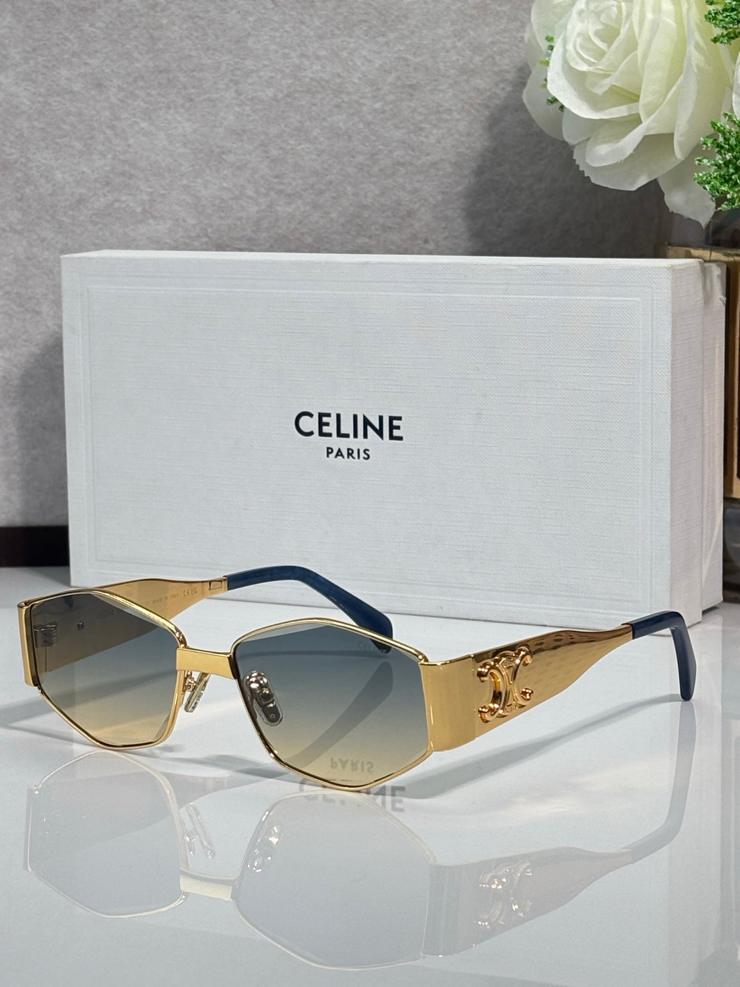 Gold sunglasses with light lenses and blue temple accents