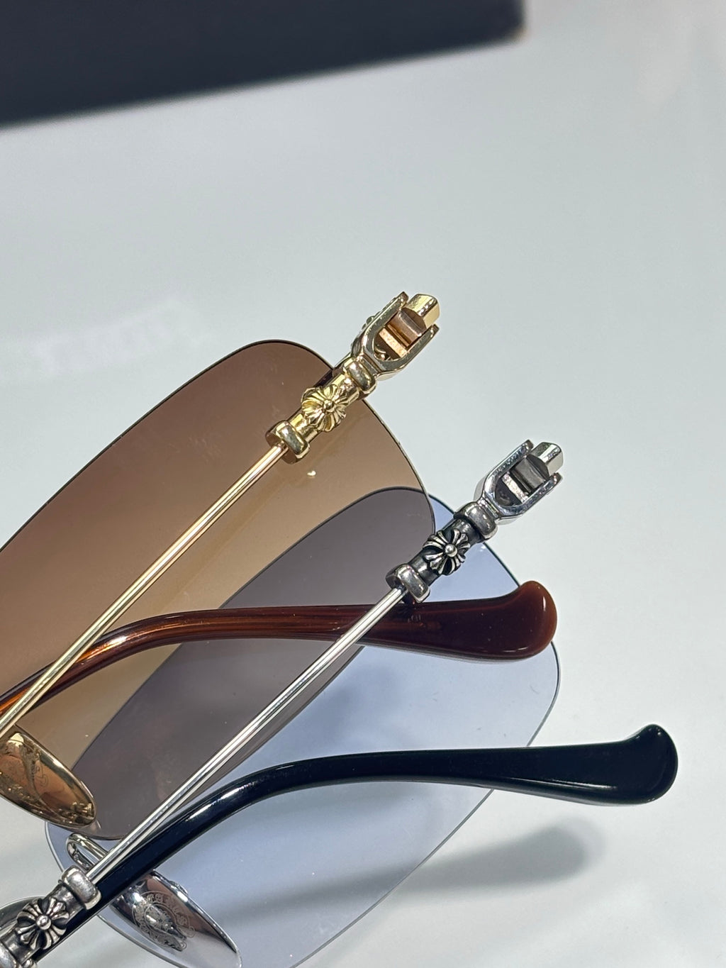 Close-up of eyeglasses temples in gold and silver with blue-tinted lens edges.