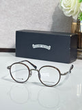 Round metal eyeglasses with dark frames and clear lenses, gold temple accents.