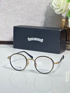 Round metal glasses with dark frames and clear lenses, gold hinge accents.