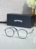 Round dark metal eyeglasses with clear lenses and curved arms, gold hardware.