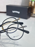 Close-up of round metal eyeglasses with dark frames and gold bridge hardware.
