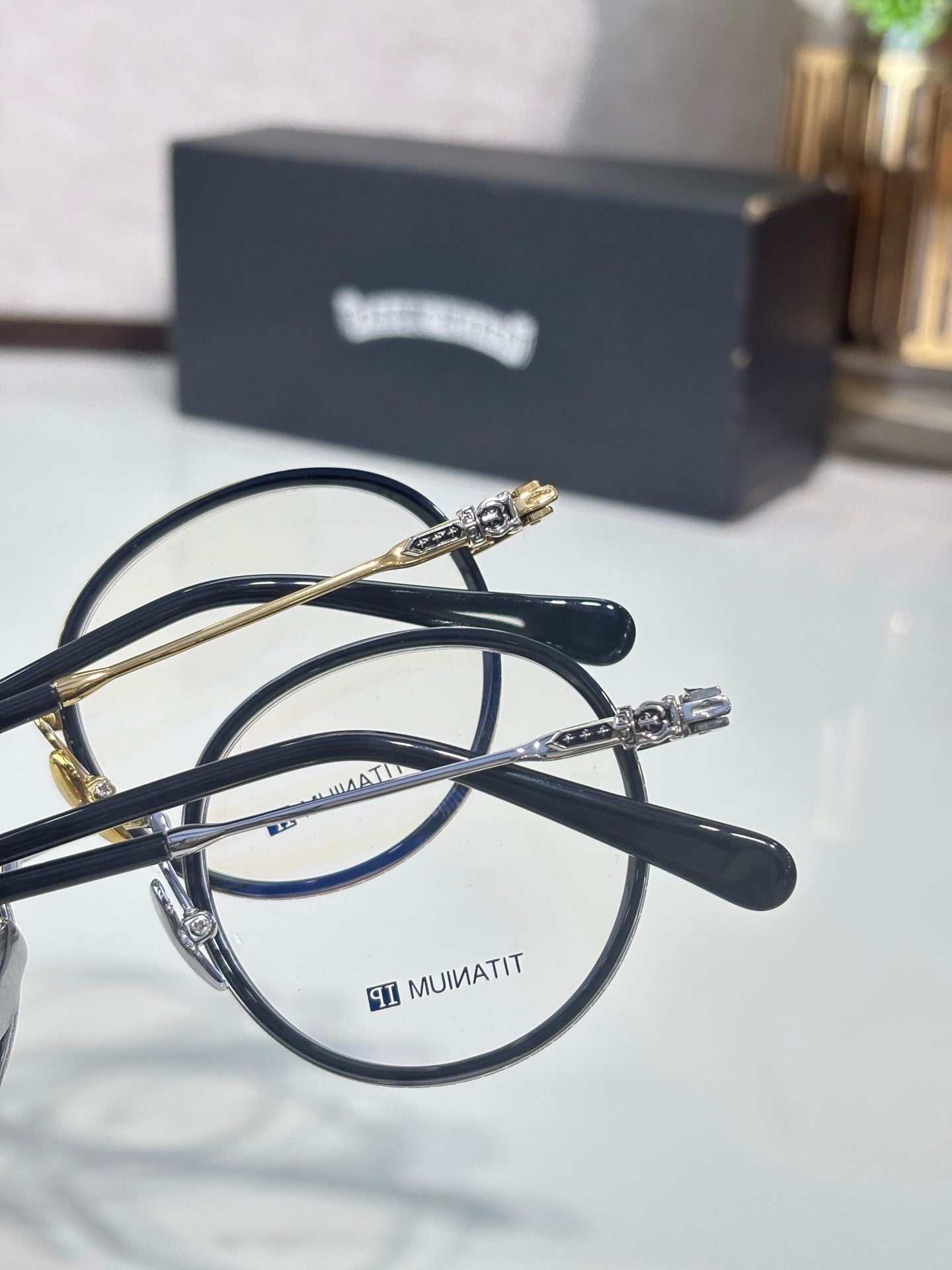 Close-up of round metal eyeglasses with dark frames and gold bridge hardware.