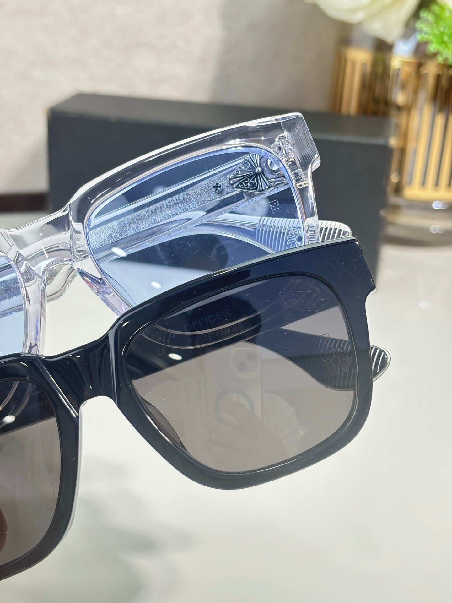 Clear sunglasses frame close-up with blue-tinted lens and chrome detailing