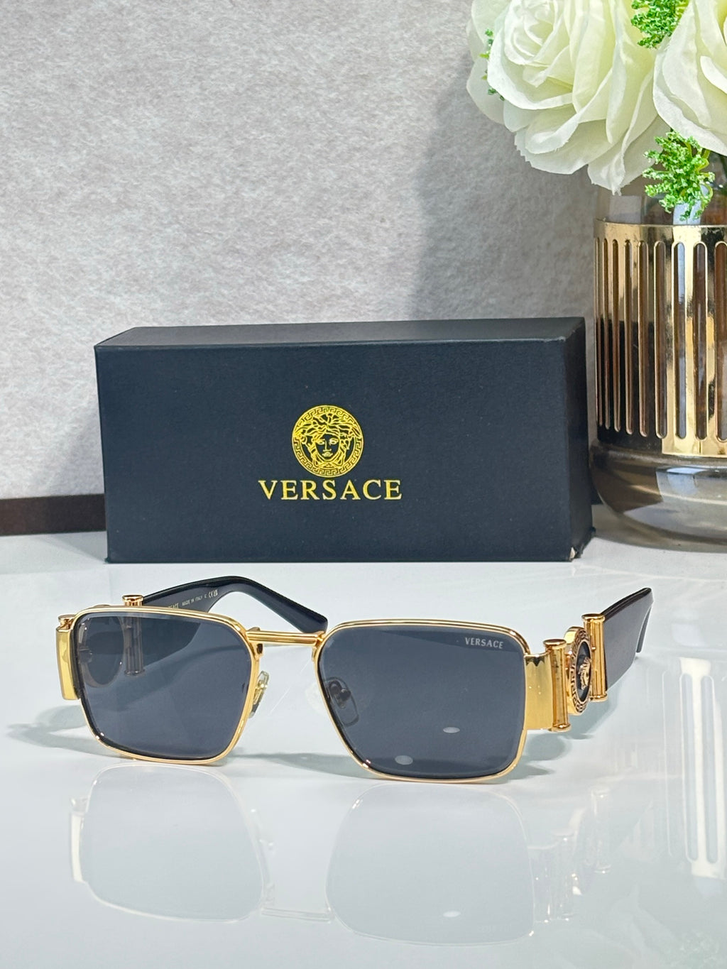 Gold-tone square eyeglasses with blue-tinted lenses and ornate side accents