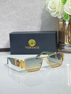 Gold-tone square eyeglasses with pale blue lenses and decorative emblem on temples