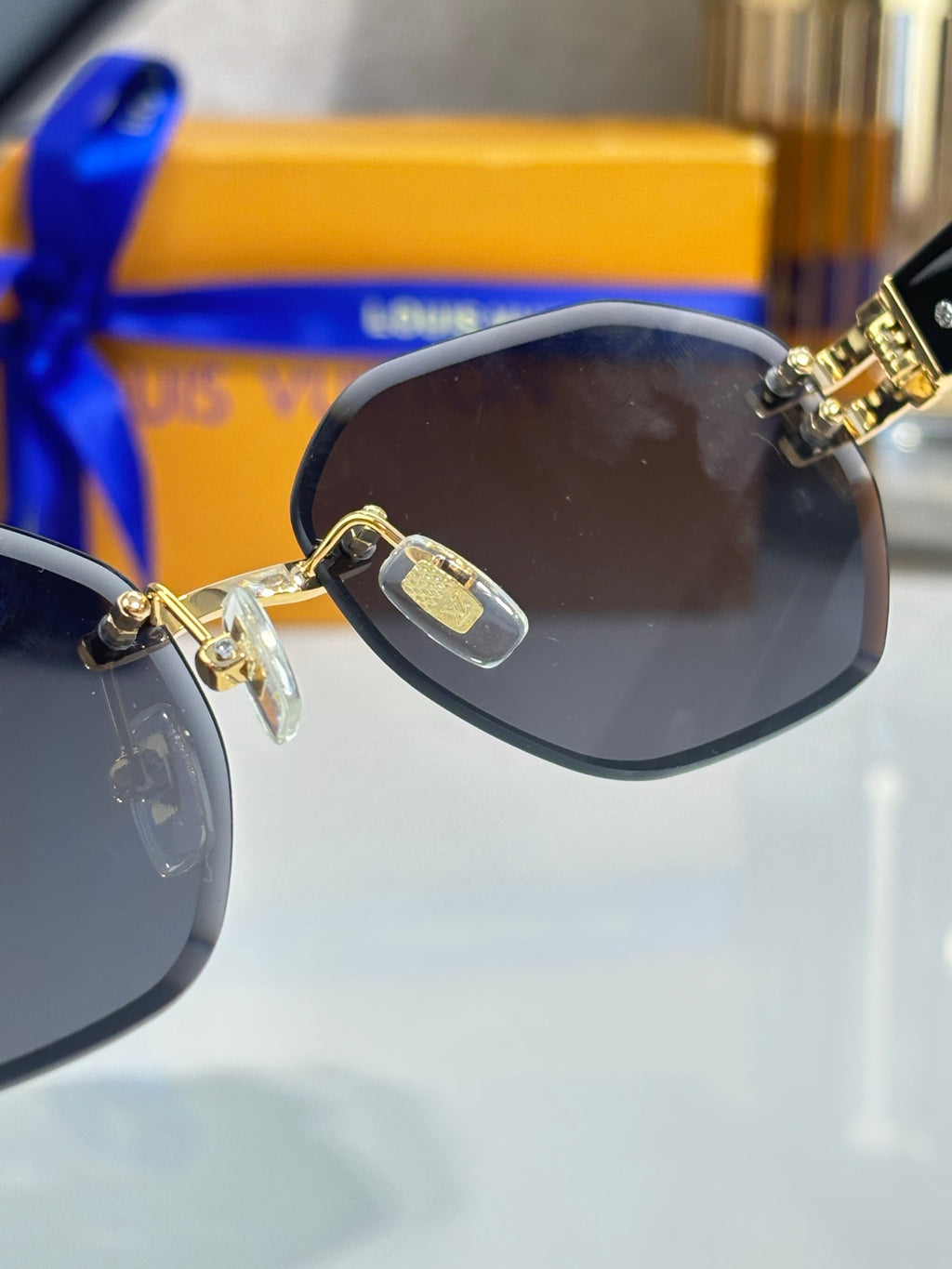Close-up round sunglasses with dark lens and gold-tone temple emblem