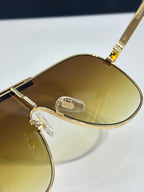 Sunglasses close-up with gold-tone frames and yellow tinted lenses, metal hinge detail