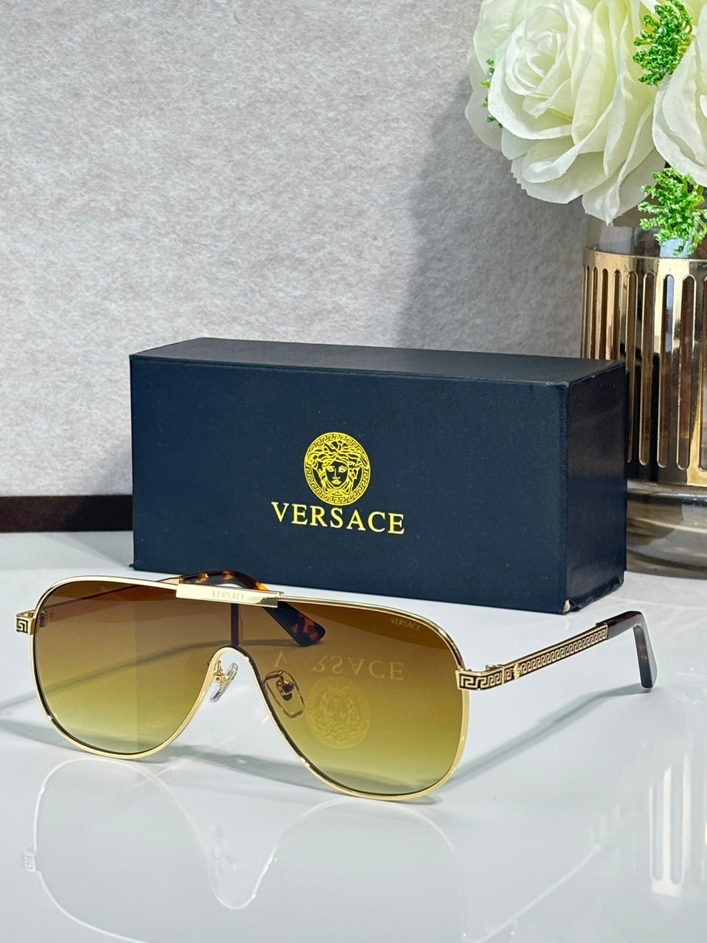 Sunglasses with gold-tone frames and amber gradient lenses, slim temple with logo pattern