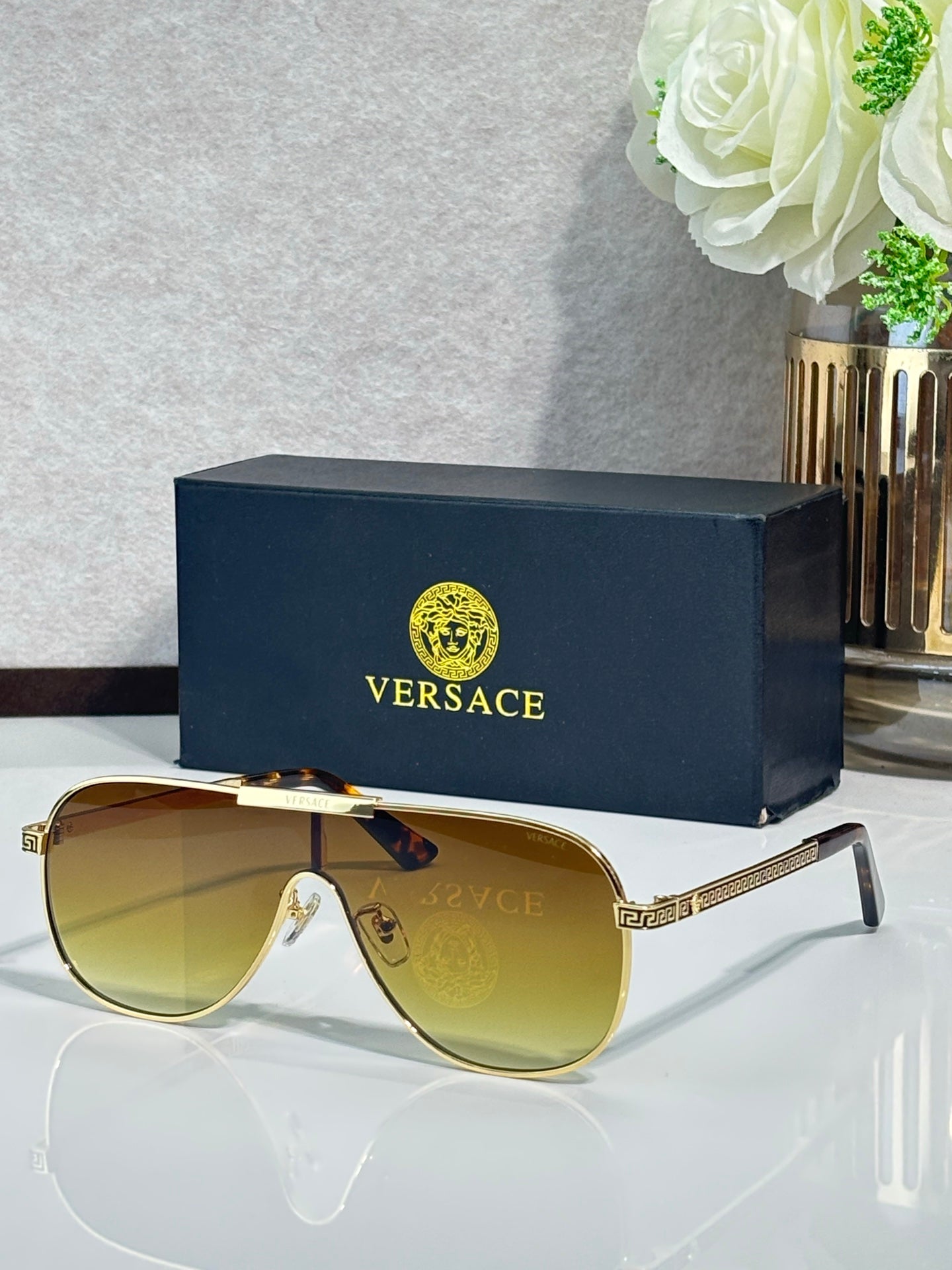 Sunglasses with gold-tone frames and amber gradient lenses, slim temple with logo pattern