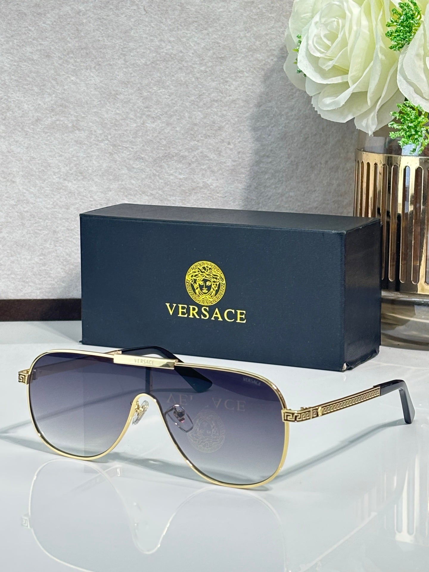 Sunglasses with dark blue frames and gradient gray-blue lenses, gold logo detail on temple