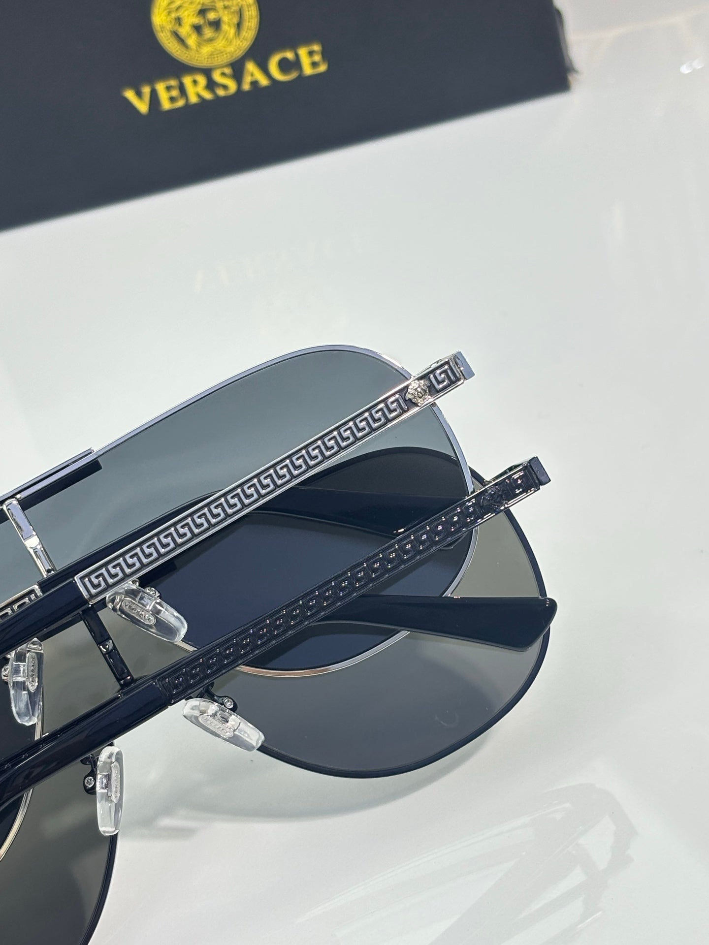 Sunglasses close-up with dark frames and dark lenses, Greek key pattern on temple