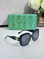 Gucci sunglasses with dark lenses, black frame and gold GG emblem at the temple.