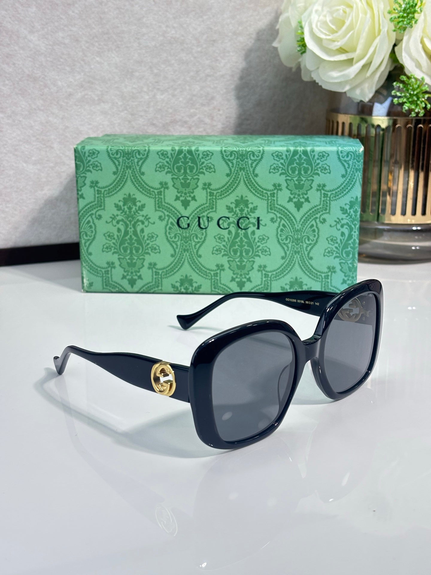 Gucci sunglasses with dark lenses, black frame and gold GG emblem at the temple.