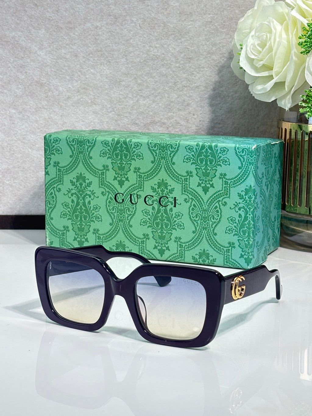 Rectangular sunglasses with dark blue frame and clear lenses, gold GG logo