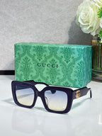 Rectangular sunglasses with dark blue frame and clear lenses, gold GG logo