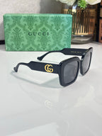Rectangular sunglasses with black frame and black lenses, gold GG logo on temple