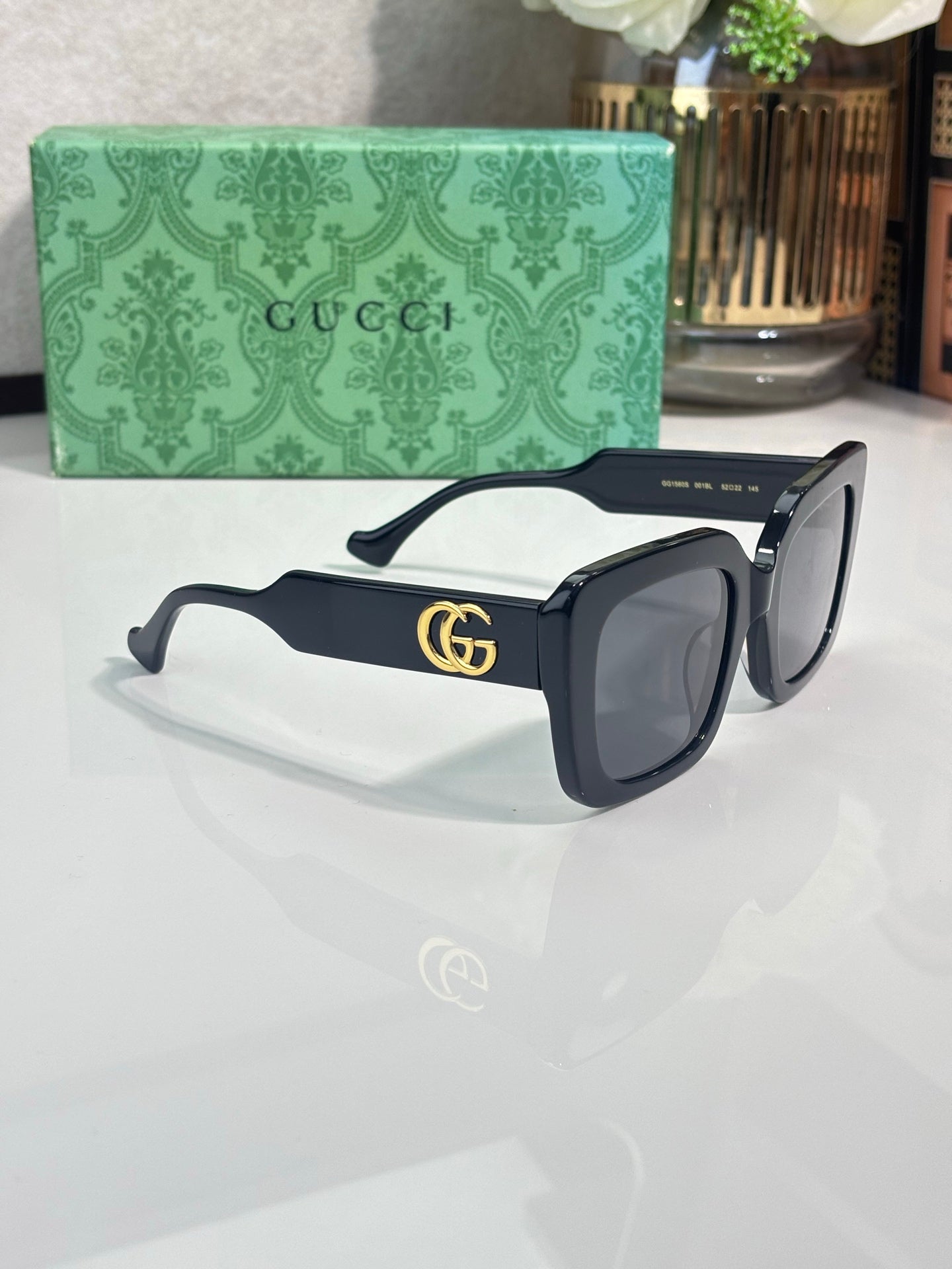 Rectangular sunglasses with black frame and black lenses, gold GG logo on temple