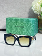 Rectangular sunglasses with dark navy frame and pale yellow tinted lenses, gold details