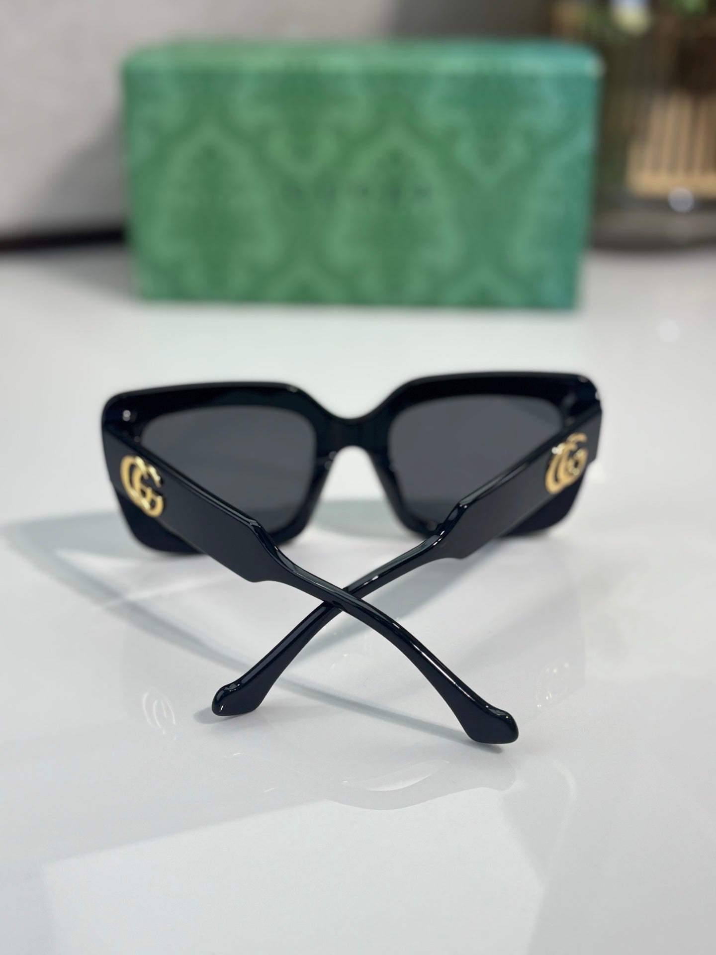Rectangular sunglasses with black frame and dark lenses, gold GG logo at side