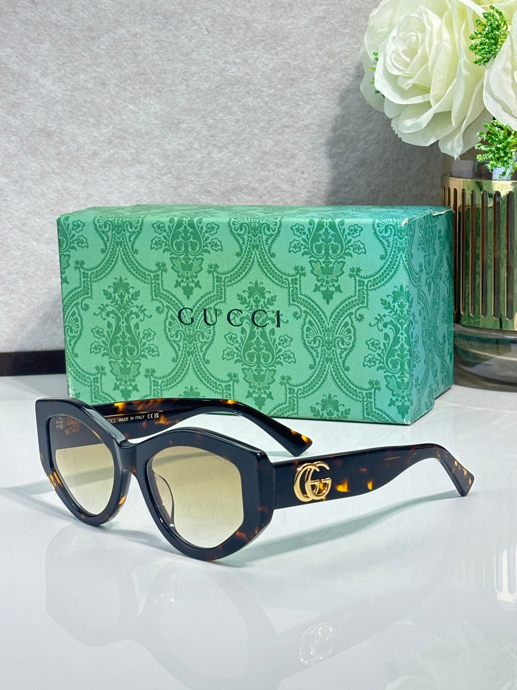 Gucci sunglasses with dark navy frame and tortoiseshell-pattern arms, gold GG logo