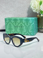 Gucci sunglasses with dark navy frame and tortoiseshell-pattern arms, gold GG logo
