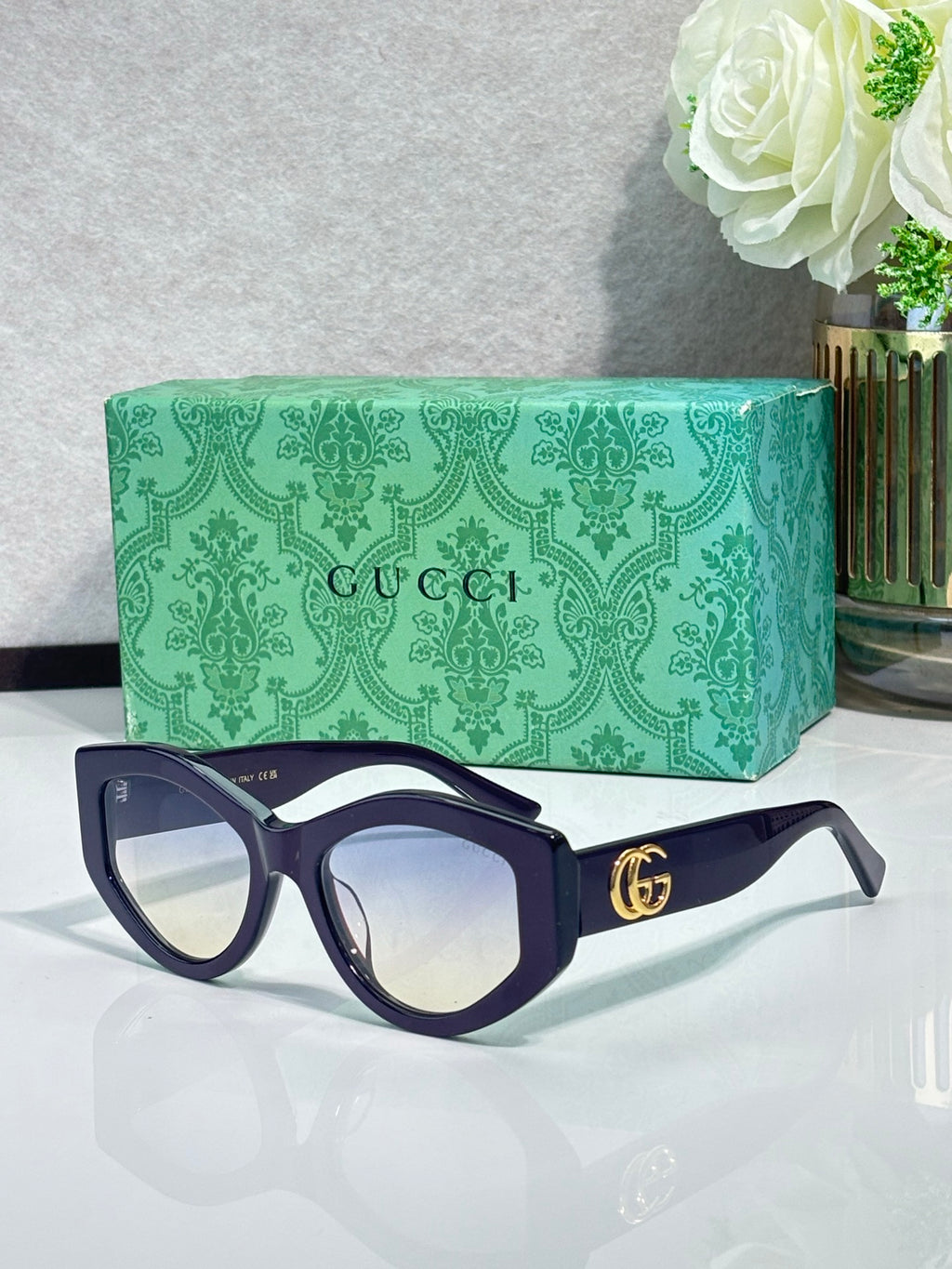 Gucci sunglasses with dark navy frame and tinted lenses, gold GG logo on side
