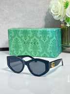 Gucci sunglasses with dark navy frame and tinted lenses, gold GG logo on temple