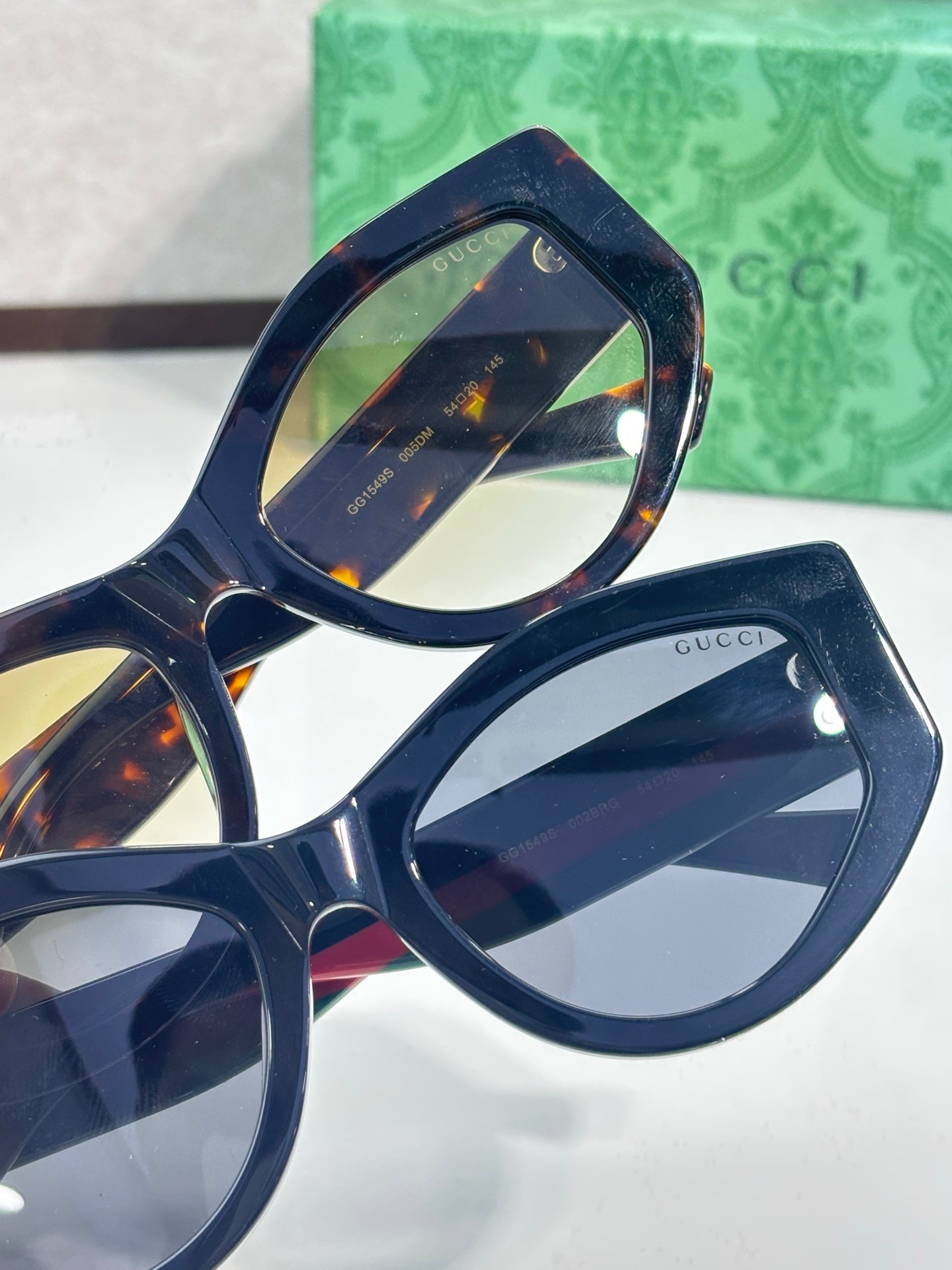 Gucci sunglasses close-up, dark navy frame with tinted lens and gold branding