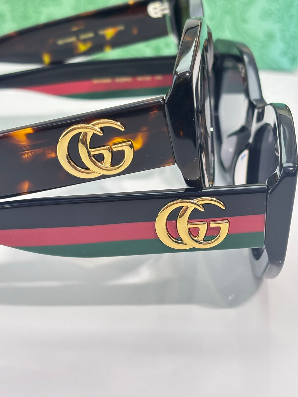 Gucci sunglasses temple close-up with gold GG logo and multicolor stripe