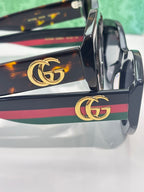 Gucci sunglasses temple close-up with gold GG logo and multicolor stripe