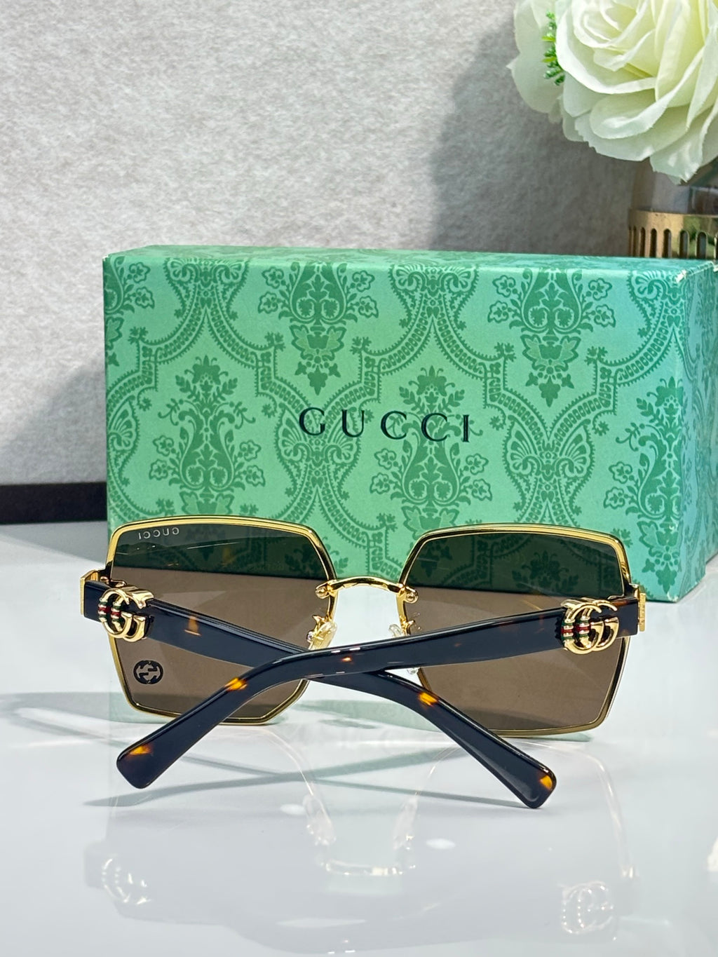 Gucci sunglasses with navy frames, gold hardware, and brown-tinted square lenses