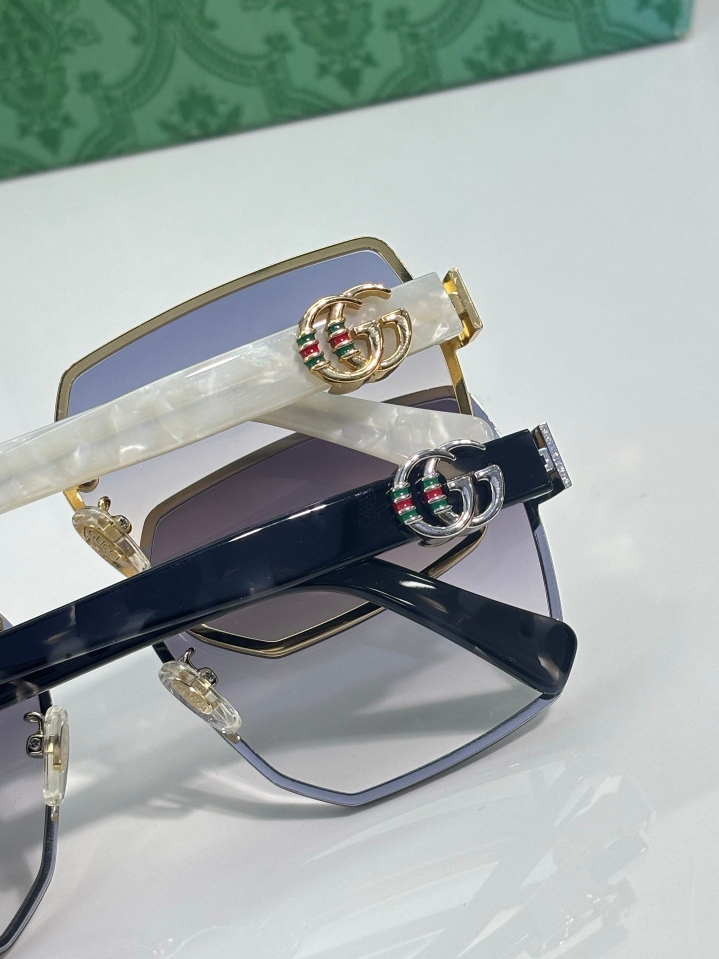 Gucci sunglasses close-up: gold frame with navy lenses and multicolor logo detail