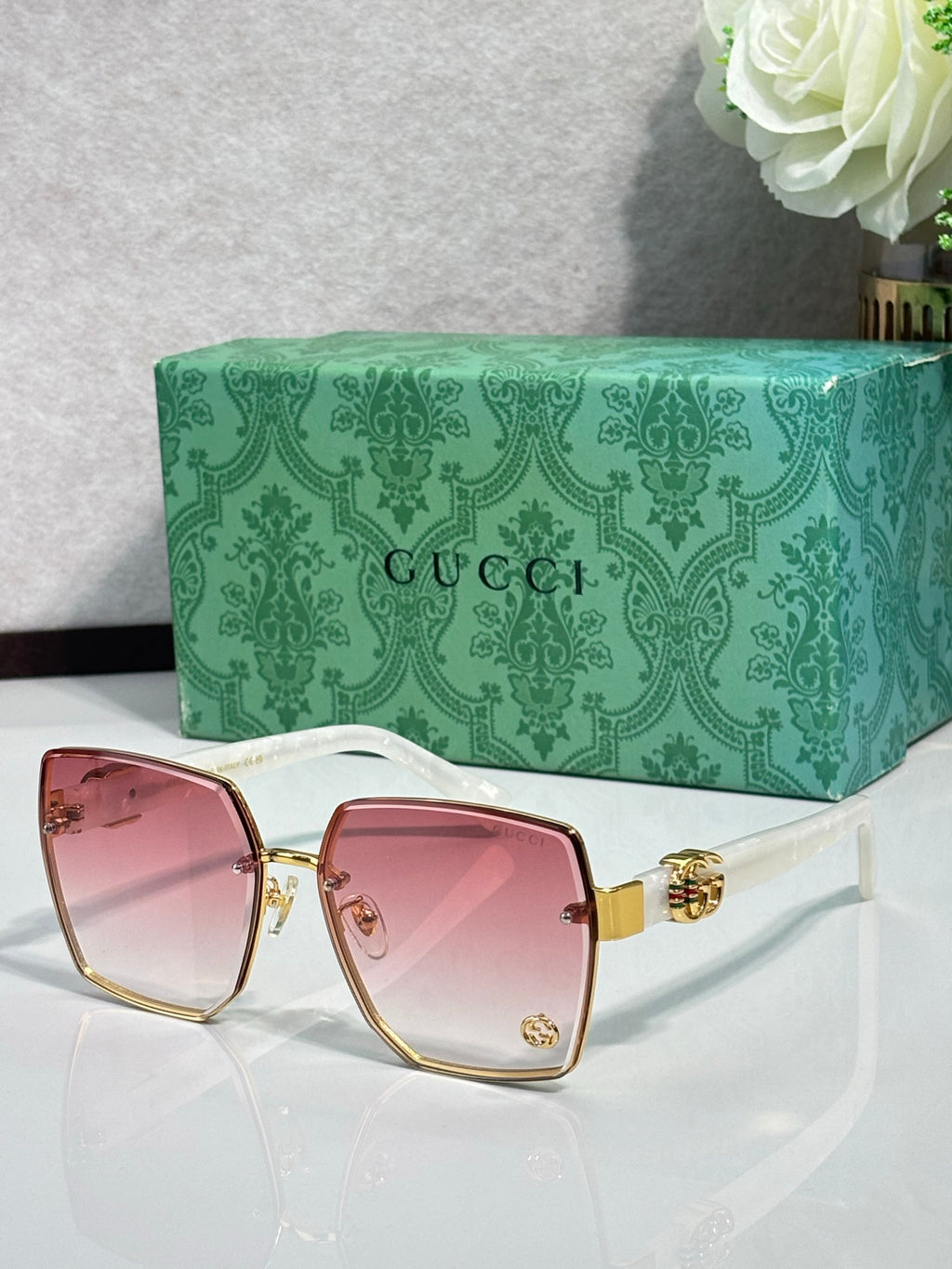Gucci sunglasses with gold frame and pink-tinted lenses, black temple detailing