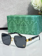 Gucci sunglasses with black square frames, dark gray lenses, and gold logo accents