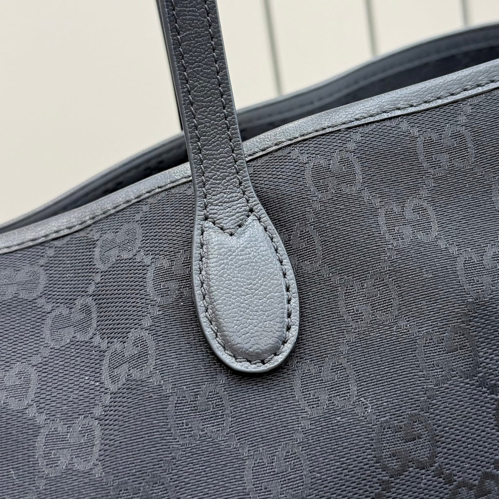 Gucci tote bag handle attachment close-up with dark gray stitched leather trim