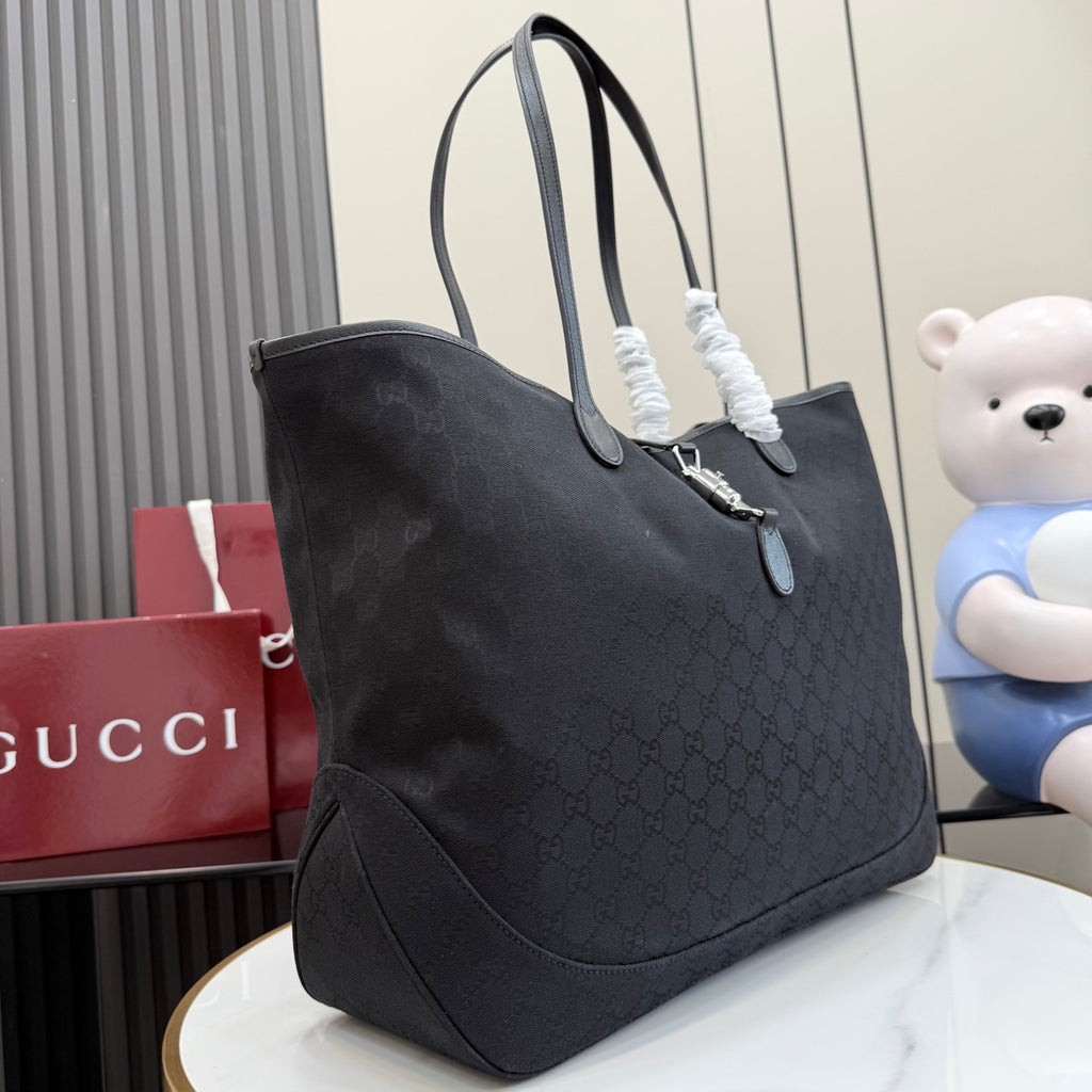 Gucci tote bag with dark textured exterior, angled view, and front pocket panel
