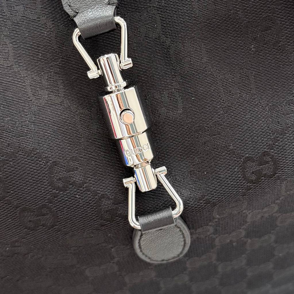 Gucci tote bag hardware detail with clasp and metal rings on dark fabric strap