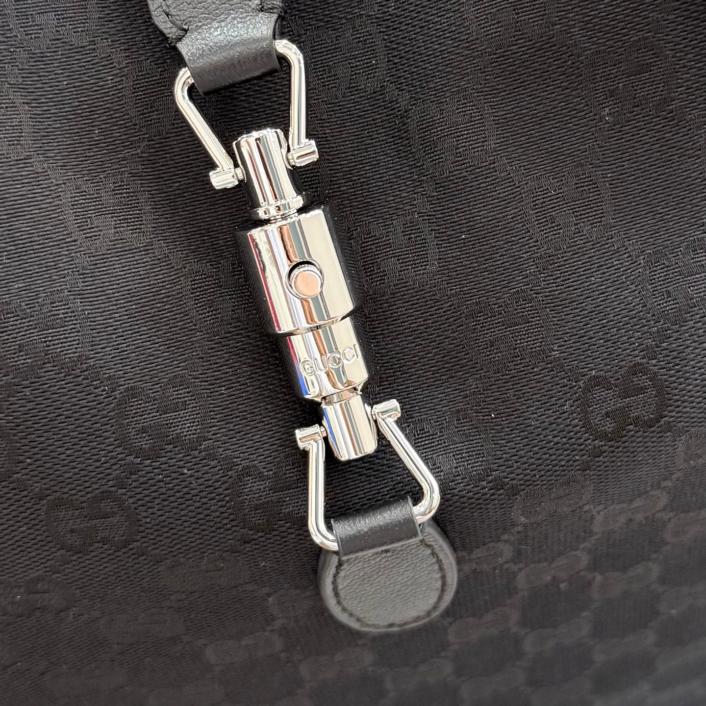 Gucci tote bag hardware detail with clasp and metal rings on dark fabric strap