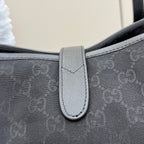 Gucci tote bag strap close-up with light gray leather tab and stitched edge