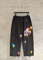 Black wide-leg pants with colorful cross patches on side panels and flap pocket