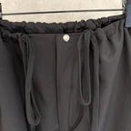 Black pants waistband detail with round button and two front drawstring ties