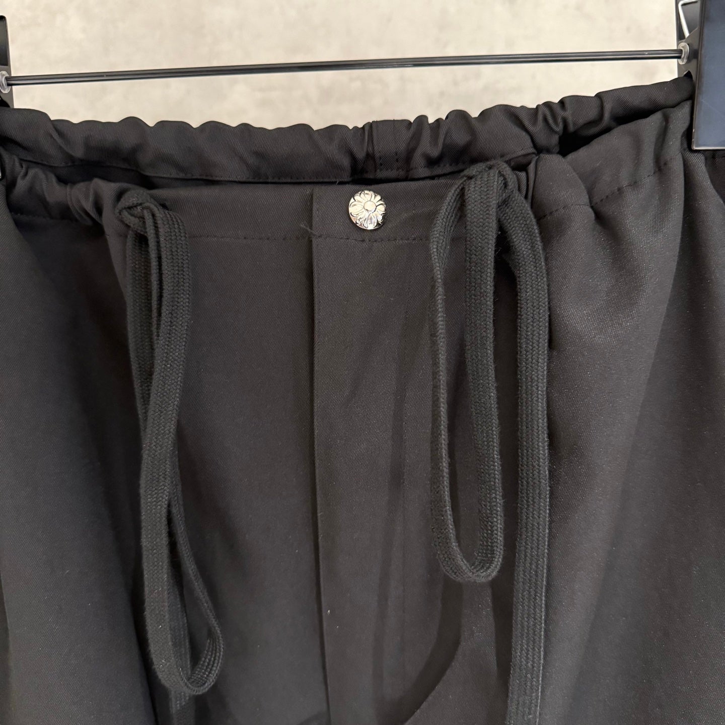 Black pants waistband detail with round button and two front drawstring ties