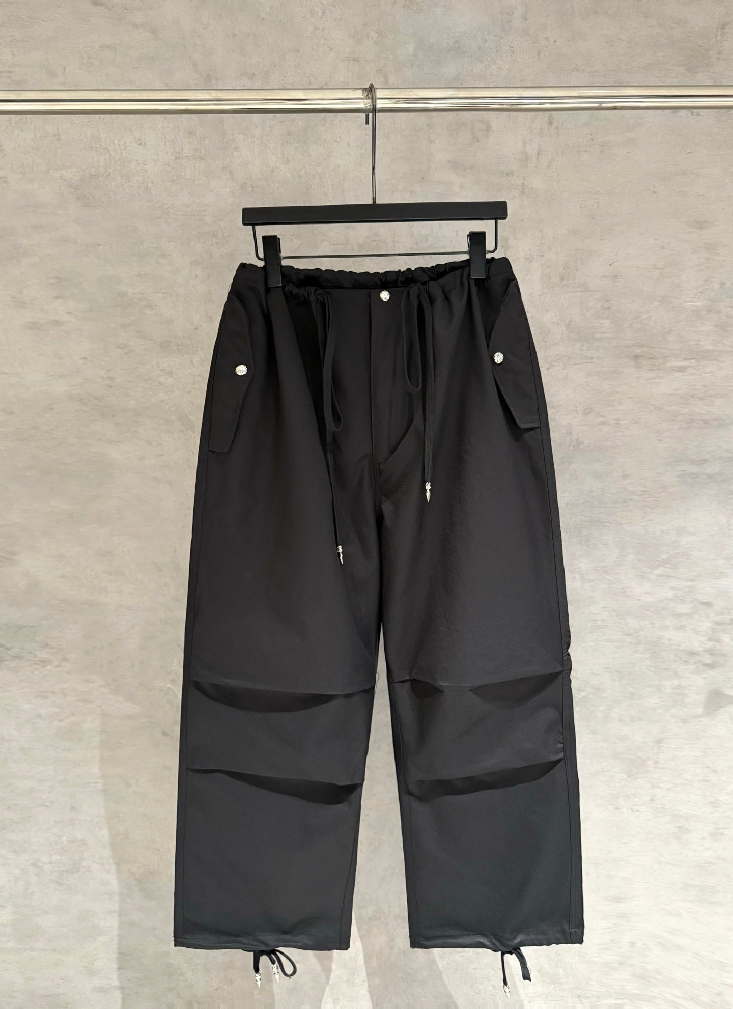 Black wide-leg pants with elastic waistband, drawstring ties and cargo pocket panels