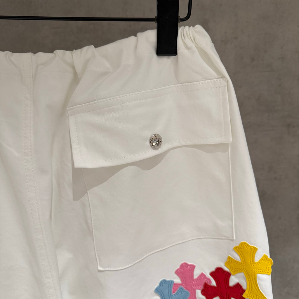 White cargo pants with front pocket flap and multicolor cross patch on thigh