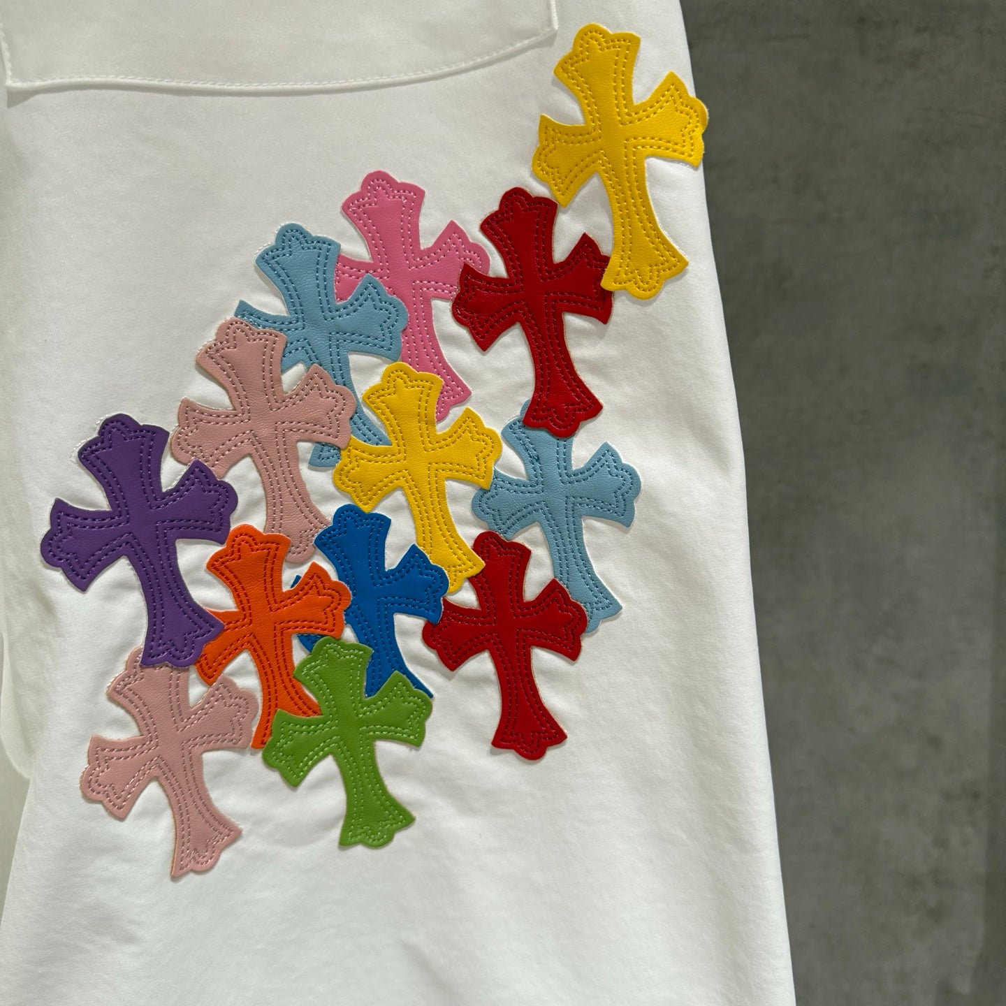 White pants with cluster of multicolor cross patches on the leg