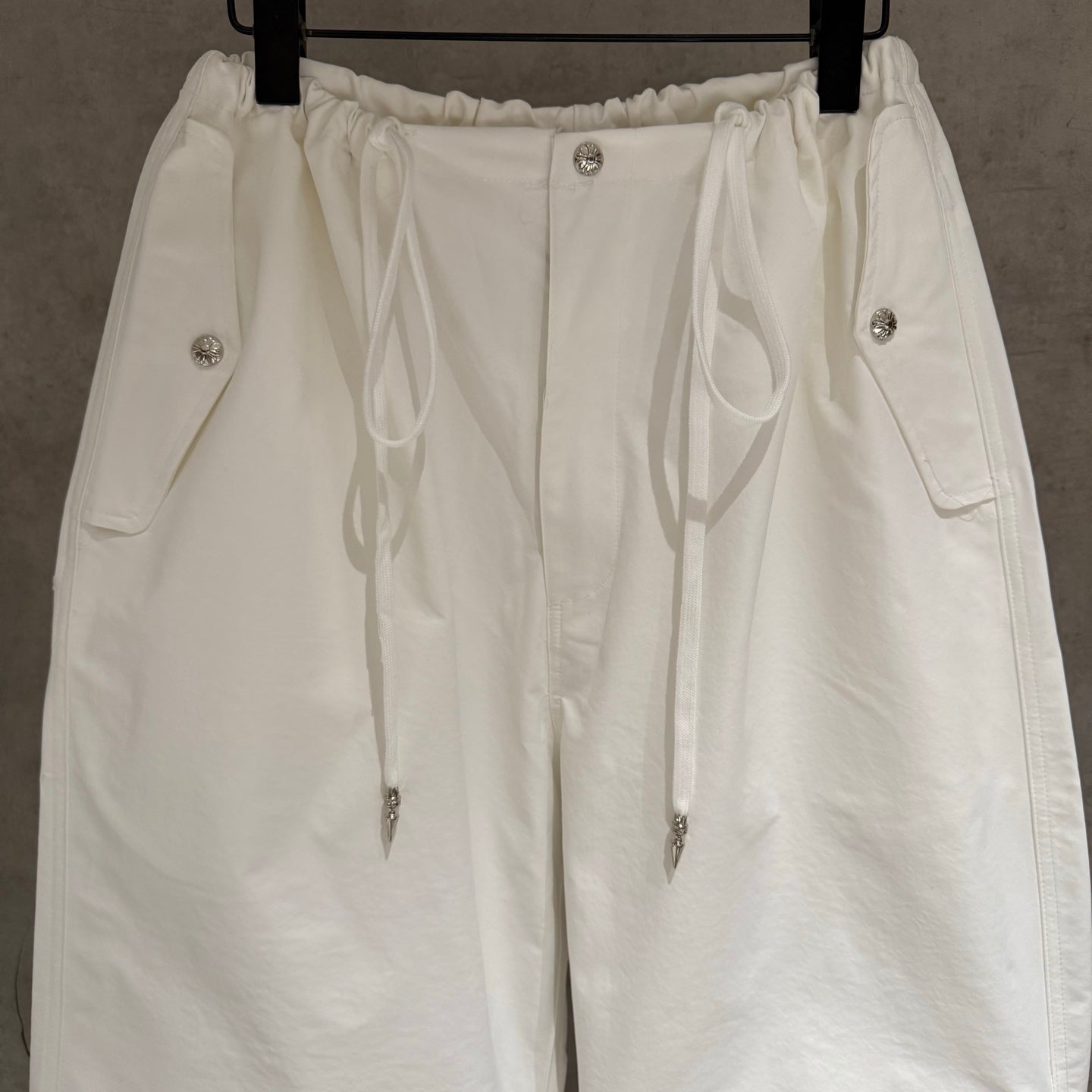 White elastic-waist cargo pants with drawstring and front metal button details