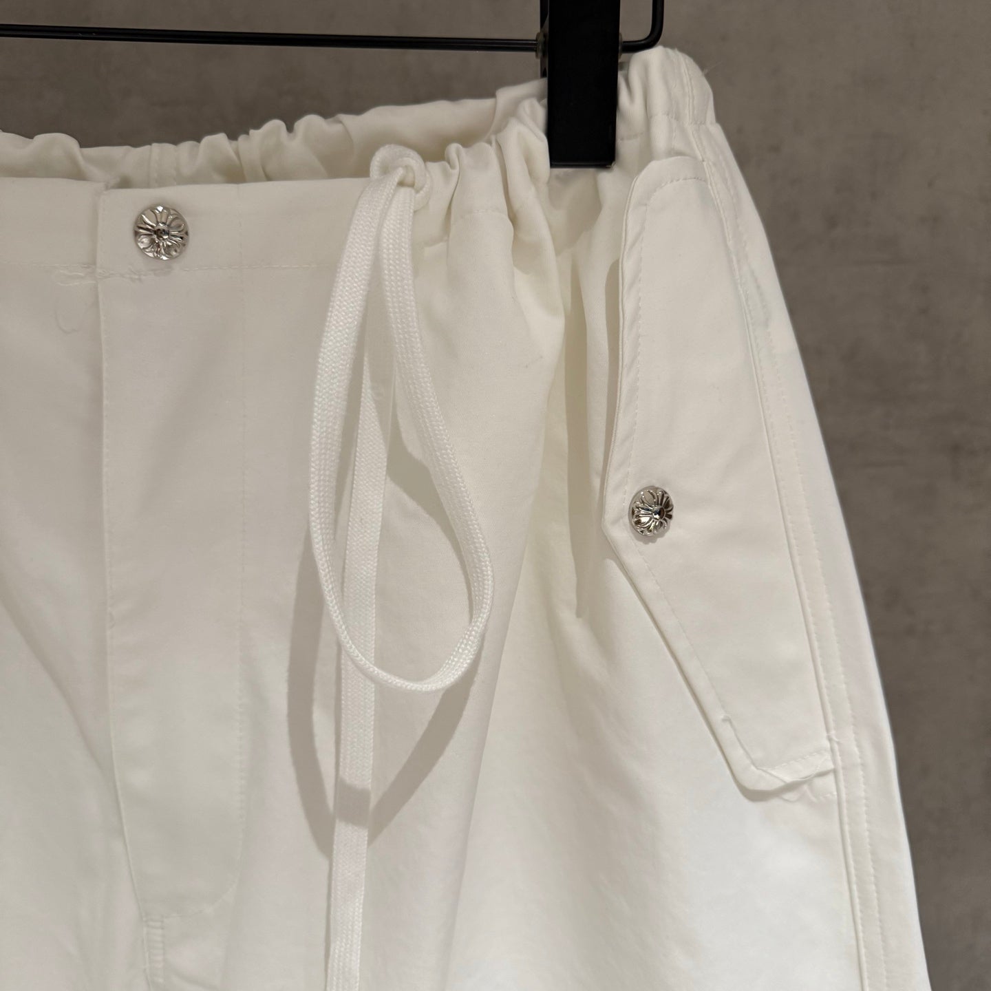 White drawstring waist pants with side pockets and metal button accents