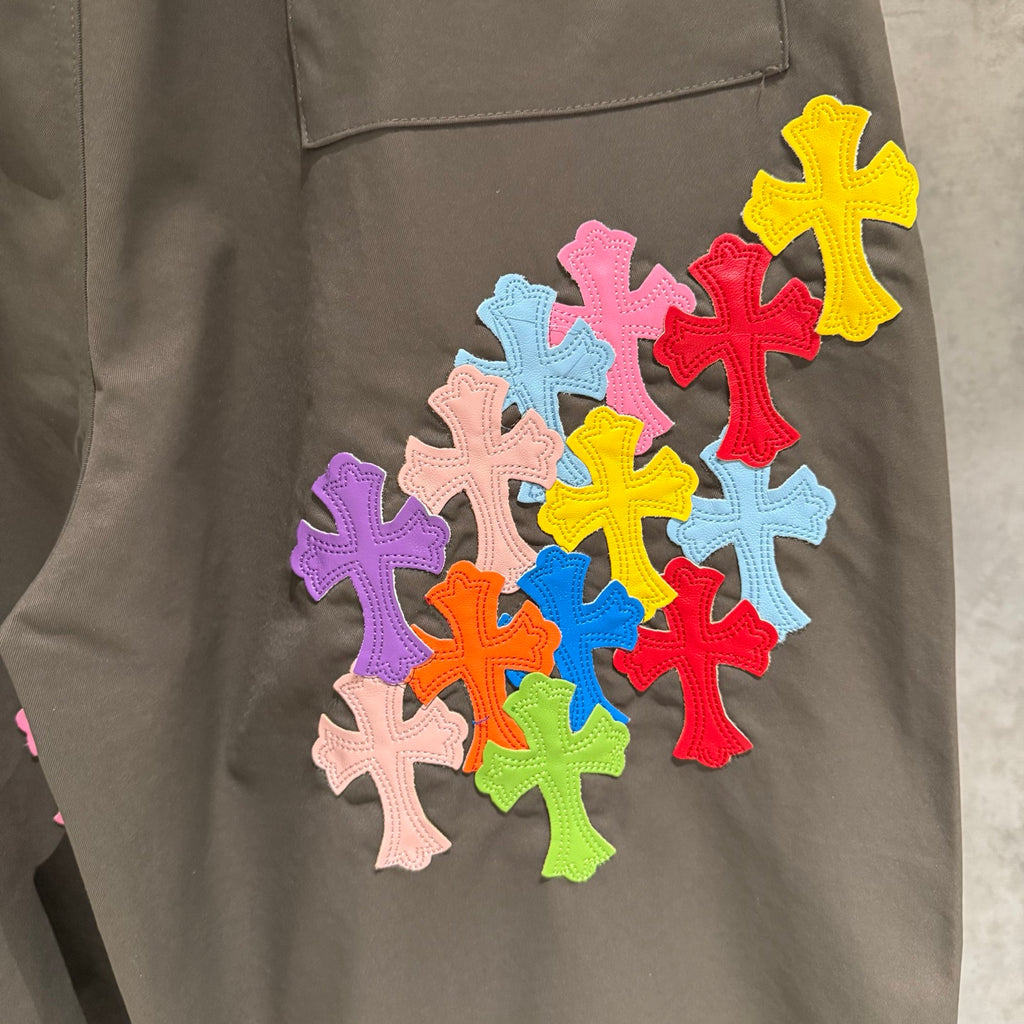 Olive cargo pants leg with multicolor cross-shaped appliques stitched on the fabric